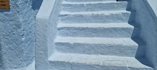 Steps lead to a bright place with white walls and sunlight shining down on a clear day