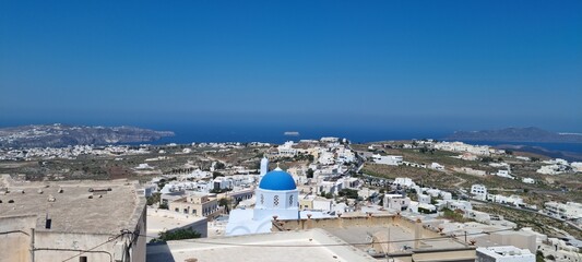 View of Santorini showing white buildings and blue dome under bright sky near the sea