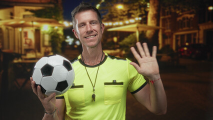 Man referee holding soccer ball with palm raised on street in neon yellow jersey and whistle visible; fair play authority.