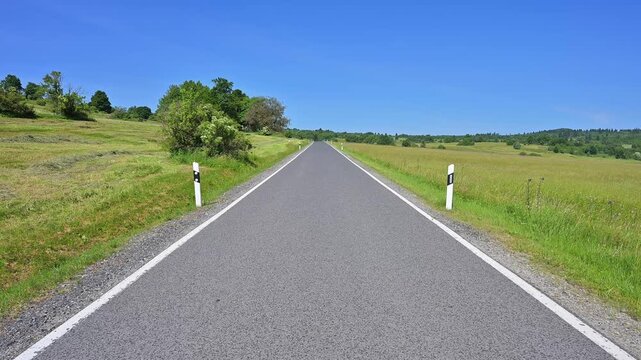 Stra&szlig;e durch eine gr&uuml;ne Sommerlandschaft mit blauer Himmelskulisse, Franzosenweg, Lange Rh&ouml;n, Oberelsbach, Rh&ouml;n, Bayern, Deutschland, Europa