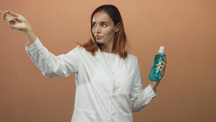 Woman doctor and young redhead in white lab coat holds a blue bottle with cap and points index...