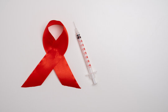 Red ribbon and syringe symbol. Global health awareness. - Powered by Adobe