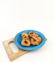 Banana chips snack in a plastic plate served on a wooden board isolated on a white background