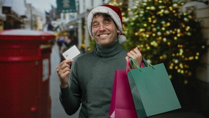 Hispanic man wearing a christmas hat smiling outdoors on a festive street while holding colorful...