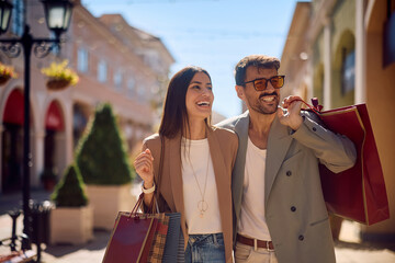 Naklejka premium Embraced couple spending a day in shopping in the city.