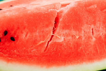 Fresh watermelon slice with cracked surface showing red flesh and black seeds