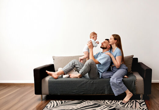 Family enjoys time together at home while playing with their baby and sharing moments of joy on a couch during a sunny afternoon