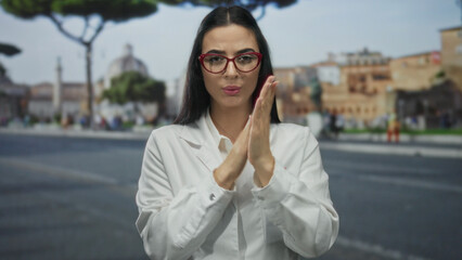 Woman scientist in white uniform with red glasses stands on an urban street appearing cold and...