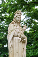 Obraz premium Statue of a queen holding a flower in a lush green setting near a park