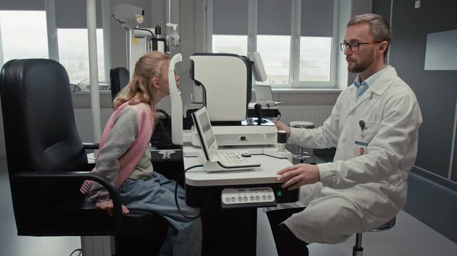 Side view shot of male doctor as optometrist using modern automated diagnostic machine and changing configuration while performing eye exam for young girl in clinic