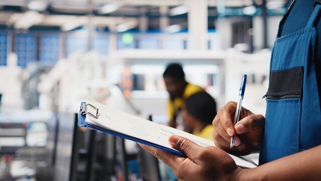 Black photovoltaics factory specialist checking configuration files, analyzing data to ensure seamless production. Solar panels manufacturing plant employee reading user manual. Camera B. - Powered by Adobe