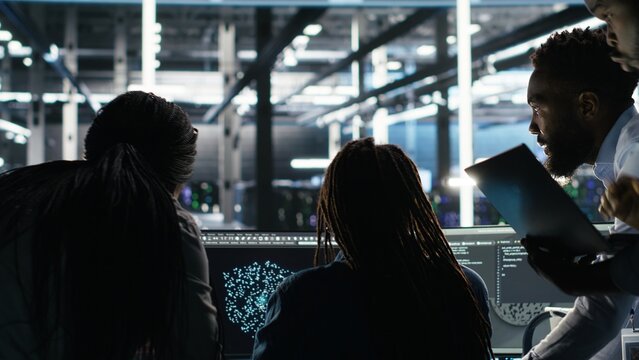 Server hub engineering team rushes to stop cyberattack targeting confidential information. Data center colleagues working together during security breach to contain virus and protect systems, camera B
