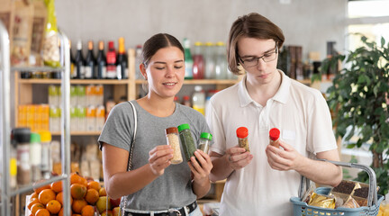 European couple in the supermarket is interested in choosing natural spices to cook dinner. Wife and husband choose spices for frying fish and meat