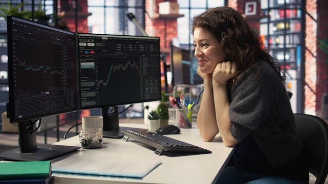 Pleased trader examines financial documentation on PC and being happy with profit, analyzing stock market movements and business trends. Interface provides live forex charts and indexes. Camera A.