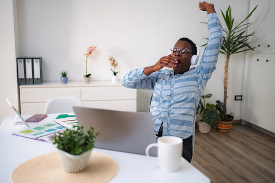 Tired man yawning and stretching during home office work