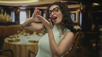 Young hispanic woman hand gesture of spending money in a restaurant inside building; playful extravagance.