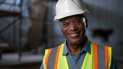 A portrait of a construction worker. He is smiling and wearing a hard hat and safety vest Stock Video