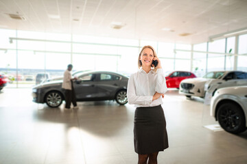 Businesswoman talking on phone at car dealership showroom