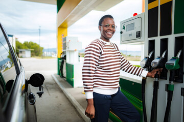 Smiling woman refueling car at gas station looking at camera