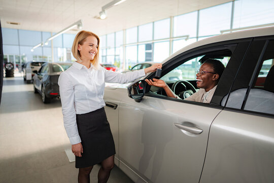 Saleswoman handing over car keys to happy customer