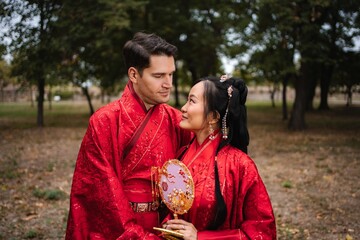 Multicultural bridal couple celebrating traditional Chinese wedding outdoors