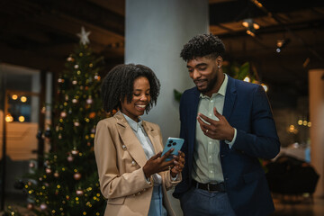 Colleagues sharing smart phone content during christmas work event