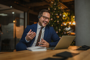 Businessman laughing during video call in festive office