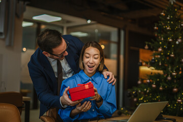 Colleagues exchanging holiday gift at office christmas party