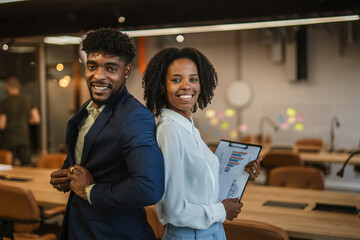 Business colleagues standing back to back smiling in office