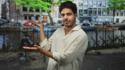 Man with open palms presenting toward a canal and bicycles beside moored boats on a street; serenity invitation.