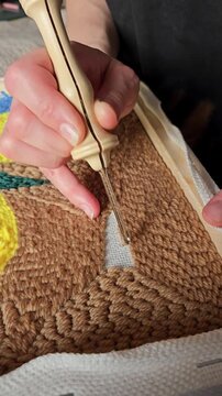 Crafting a vibrant piece of art through hooking yarn at a crafting table in a cozy room. punch needle work.