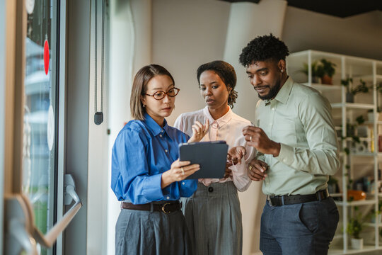 Diverse business team collaborating and discussing on digital tablet