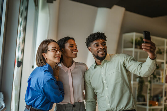 Diverse business colleagues taking a cheerful selfie in office