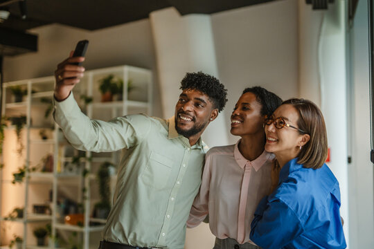 Diverse business colleagues taking a cheerful selfie in office