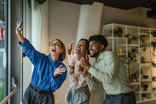 Diverse friends taking office selfie bonding and laughing