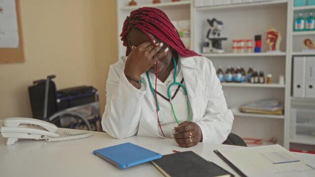 Woman doctor in clinic office with stethoscope reviewing tablet and documents, displaying focus and concentration at workplace interior. - Powered by Adobe
