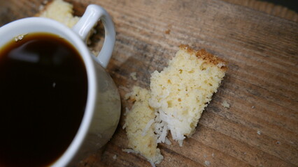 A cup of coffee next to a slice of cake. A cup of coffee on the table. A piece of cake on the table. An espresso. A pie.