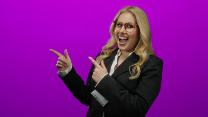Woman pointing enthusiastically in business attire against a vibrant purple background, radiating...