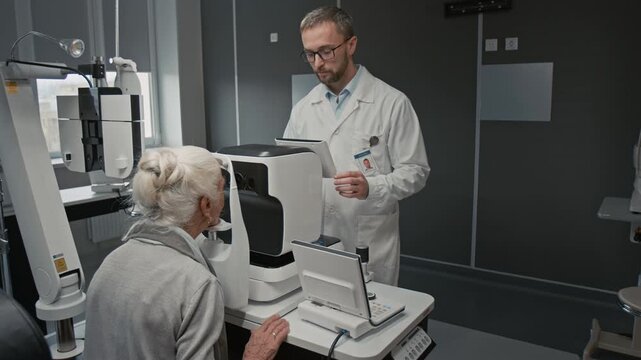 Medium shot of male doctor as ophthalmologist conducting optometric exam on senior patient using modern diagnostics machine in clinic, copy space