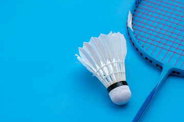 Cream white badminton shuttlecock and racket on floor in indoor badminton court, copy space, soft and selective focus on shuttlecocks.	