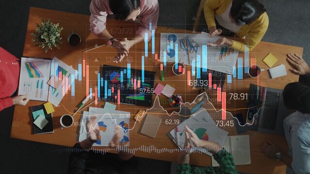 A vibrant workspace showcases a diverse group of professionals engaged in financial analysis, using charts and graphs to drive data-informed decisions and strategies. Raster - Powered by Adobe