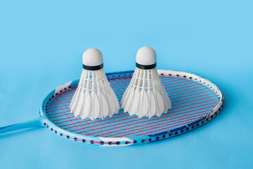 Cream white badminton shuttlecock and racket on floor in indoor badminton court, copy space, soft and selective focus on shuttlecocks.	