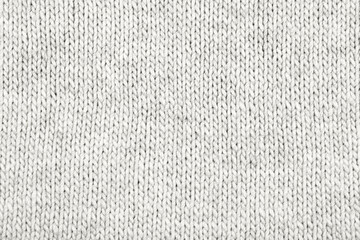 Demonstrating the colors of 2026 - Cloud Dancer. Knitted gray white background. Large knitted fabric with a pattern. Close-up of a knitted blanket. Color concept.