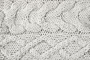 Demonstrating the colors of 2026 - Cloud Dancer. Knitted gray white background. Large knitted fabric with a pattern. Close-up of a knitted blanket. Color concept.