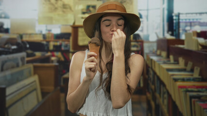 Woman wearing strawhat and holding ice cream cone with both hands and smiling in a historic library...