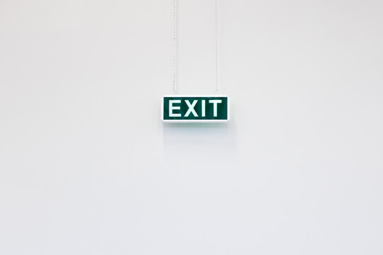 Emergency exit sign isolated on white minimalist wall. Clean and simple emergency exit sign on neutral background, ideal for safety, architecture and instruction concepts.