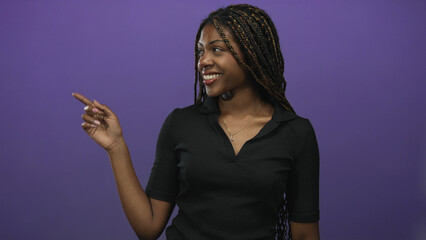 Woman pointing finger with left hand and making ok sign with right hand in purple studio wearing...