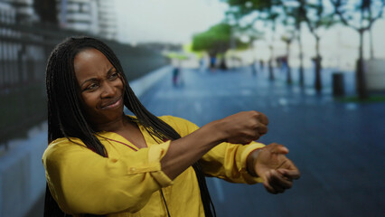 Woman in yellow mimicking a tug on an imaginary rope in urban street setting outdoor expressing...