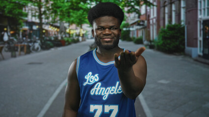Man reaches hand palm up on city street wearing blue basketball jersey; inviting outreach connection community.