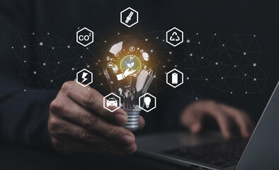 Innovative concept of renewable energy and sustainable technology. Businessman holding light bulb with green energy icons symbolizing eco-friendly innovation, and environmental responsibility.